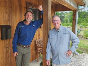 Doug Davis and Jeff Meyer, co-founders of The Farm at Okefenokee, pose on the porch of a cypress cabin