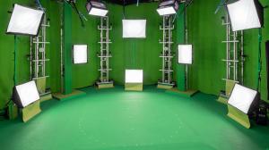 Tall lights surround a green screen covered room