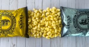Two bags of Oogie's Puffcorn spilled on a table, showcasing the newest addition to their snack line.