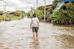Man walks through flooded village.