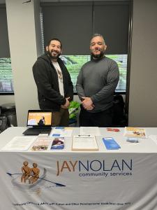 Two JNCS staff at a booth at a resource fair for individuals with disabilities.
