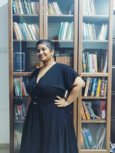 Crisenta Almeida, the founder and CEO of Content Garrage, poses in front of her home library.