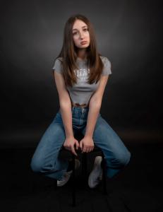Picture shows  author  Andrea Matei sitting on a stool wearing jeans and  a top