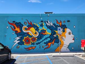 A mural of a woman's head. Coming out of her head are cacti, smoke, planets, stars and flames