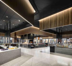 A lobby with restaurant spaces, terrazzo floors, and patterned ceiling.