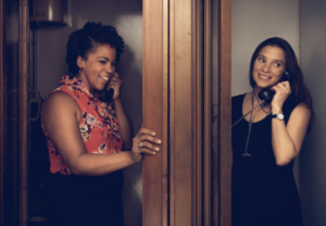 A photo of Cassie Haynes and Jean Friedman-Rudovsky in adjoining phone booths