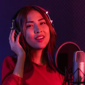 A female voice actor with headphones and a microphone