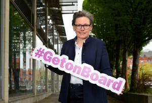 Picture of Eileen Mullan, founder, UK Boardroom Apprentice holding a #GetOnBoard sign