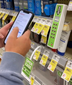 Image of shopper using phone to scan a QR code and open a locked case to get product.