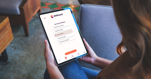 A patient using the Clinitouch software app to monitor their health remotely at home. They are sat on the sofa using a digital tablet.
