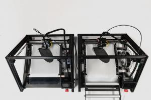 Two of the 3D conveyor belt printers photographed from above. On both, shoe insoles are created from black, flexible filament material (TPU)