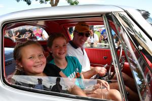 A family cruising in a classic vehicle.