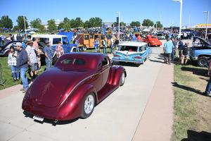 Classic cars cruising the show grounds with people milling about.