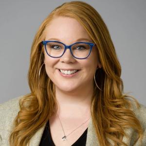 Headshot of Jill T. Whiskeyman from the shoulders up, smiling, wearing a business casual top and a butterfly necklace.
