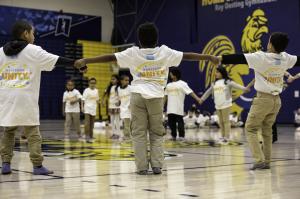 Children from ELAMS school performing a dance in a gym