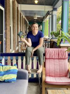 Baltimore author Willow Night sits on her rowhouse porch holding a copy of her book.