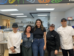 A group of five volunteers and staff members of Sonoma Family Meal pose in their kitchen that provides meals to the food insecure people of their community.