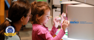 young museum visitor close up with exhibit with parent at miSci