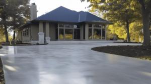 A gray driveway which has a wet look to it as a result of recently pouring and finishing the surface of the concrete driveway