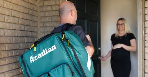 An Acadian Health mobile health paramedic greets a patient at their front door.