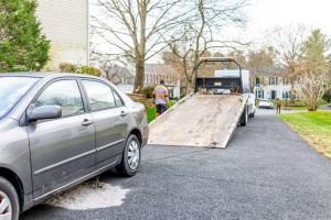 A white tow truck provided by Blaine Towing Services preparing to load a grey sedan onto the flatbed