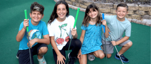 group of kids kneeling holding golf clubs during a round of mini golf at Boomers