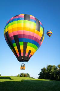 Two rainbow-colored hot air balloons ascend into sunny skies for Louise Vadasz's Wish of a Lifetime.