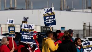 UAW workers on strike in front of automotive plant asking for shorter work week.