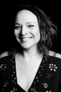 Black and white photo of film director Deborah Correa, smiling at camera