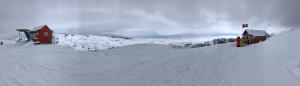 The image is a panoramic photo of the summit of Soldier Mountain showing the Bird’s Eye Lift, also known as Chair 2, on the left and the ski patrol shack on the right.