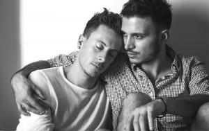Two young men seated closely, sharing an intimate moment that reflects their deep connection and affection for each other.