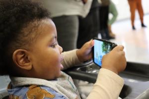 Black baby watching cell phone