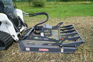 Skid steer loader with brush cutting attachment hooked up with hydraulic hoses.