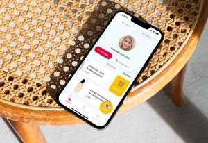A mobile phone on a chair. The screen on the phone is the homescreen from the wishlist app Cupio.