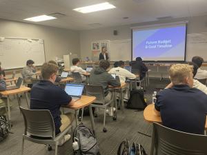 A teacher in front of a class teaching Money Path