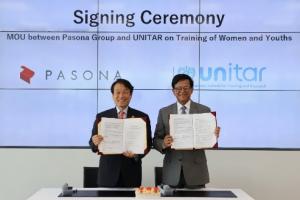Two men holding up documents in front of a projector screen