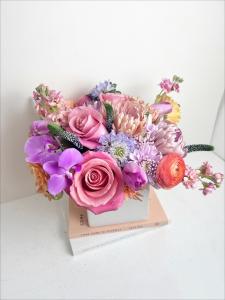 Pastel pink, white, ivory, and lavender floral arrangement with roses, orchids, ranunculus and more