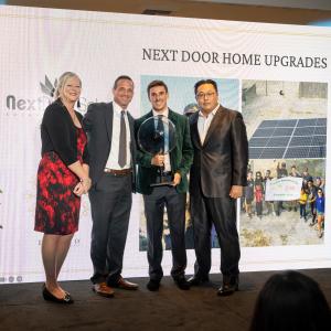 Wells of Life staff presents Corporate Partner of the Year Award to Sam Smith and Johnny Rhee of Next Door Home Upgrades with circular glass art piece