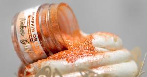 orange edible glitter on a white frosted cupcake