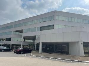 An exterior view of a white, four-story office building during a cloudy day.