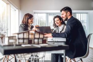 Side view image of young happy family sitting in consulting office, making property purchase.