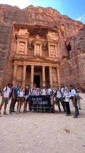 Mixed group in Petra, Jordan carrying a flag that says 'Charity Challenge'