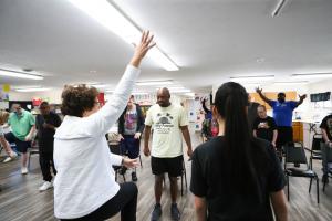 A man leads a chair exercise class for a group of people at the Carousel Center