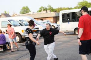 A visitor and a staff member of the Carousel Center playfully dance together outside at an event