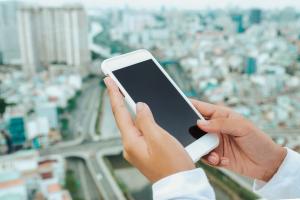 Person holding a phone with a city landscape in the background.