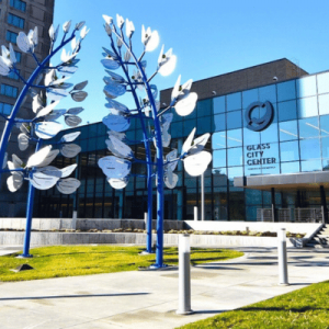 View of the Glass City Center building from a different view with metal tree sculptures in front of the building
