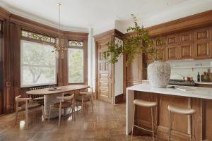 An interior design project of a kitchen in a Brooklyn Brownstone, executed by Arsight and Artem Kropovinsky, featuring a restored oak millwork, kitchen island, a dining table in the bay window, and the powder room