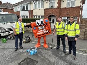 The Ultracrete mascot stands with the pothole filling team all smiling at the camera