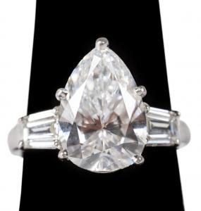Dazzling 5.64-carat, pear-shaped brilliant faceted diamond of SI-2 clarity and E color, flanked by two modified bullet cut step faceted diamonds of VS-1 clarity and E/F color (est. $80,000-$125,000).