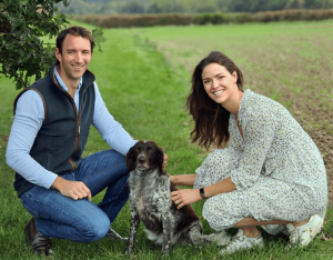 Image of Stowable Co-founders - James and Jen Mugleston standing in a field smiling at the camera with their dog